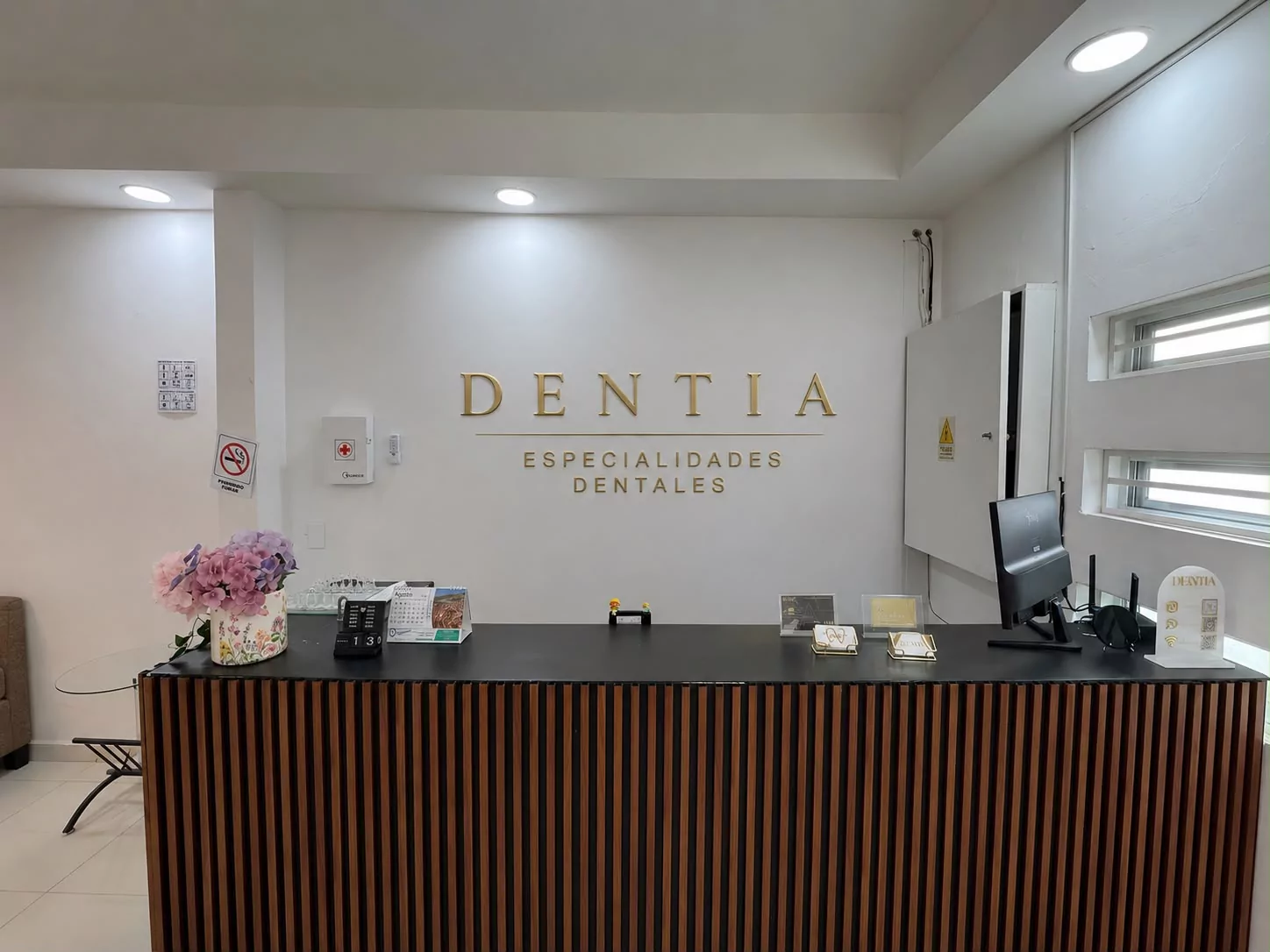 Recepción de Dentia con mostrador de madera y logotipo dorado